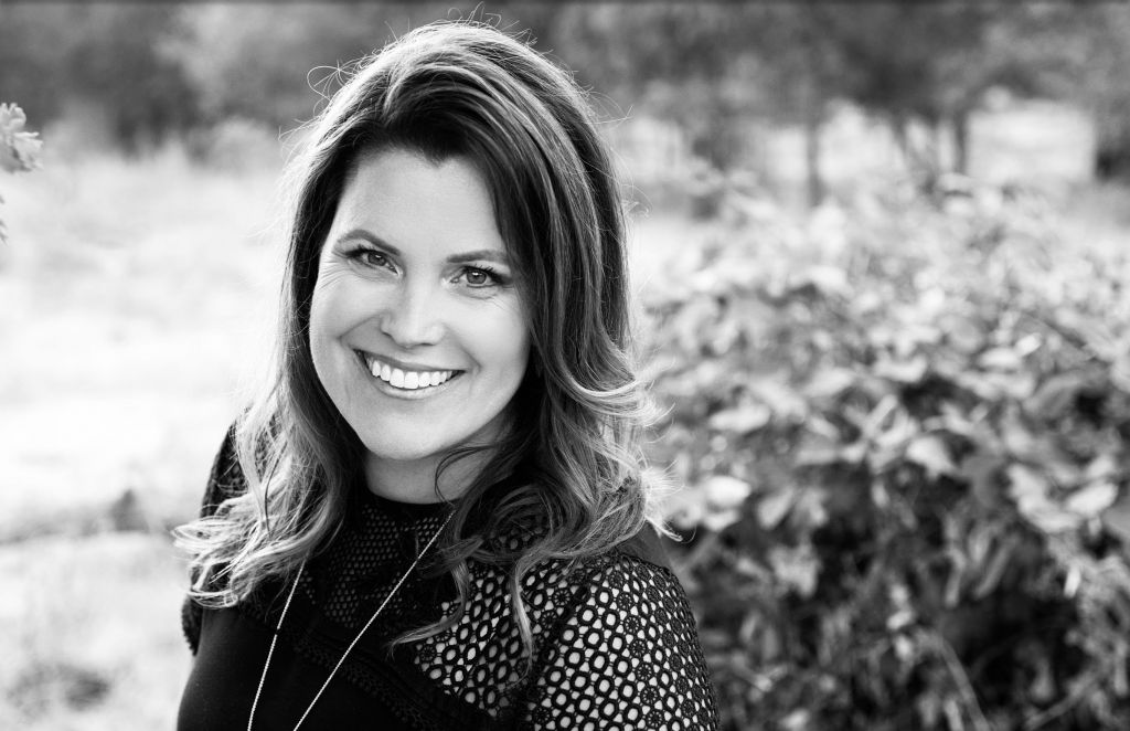 Black and white photo of a woman posing in front of a bush