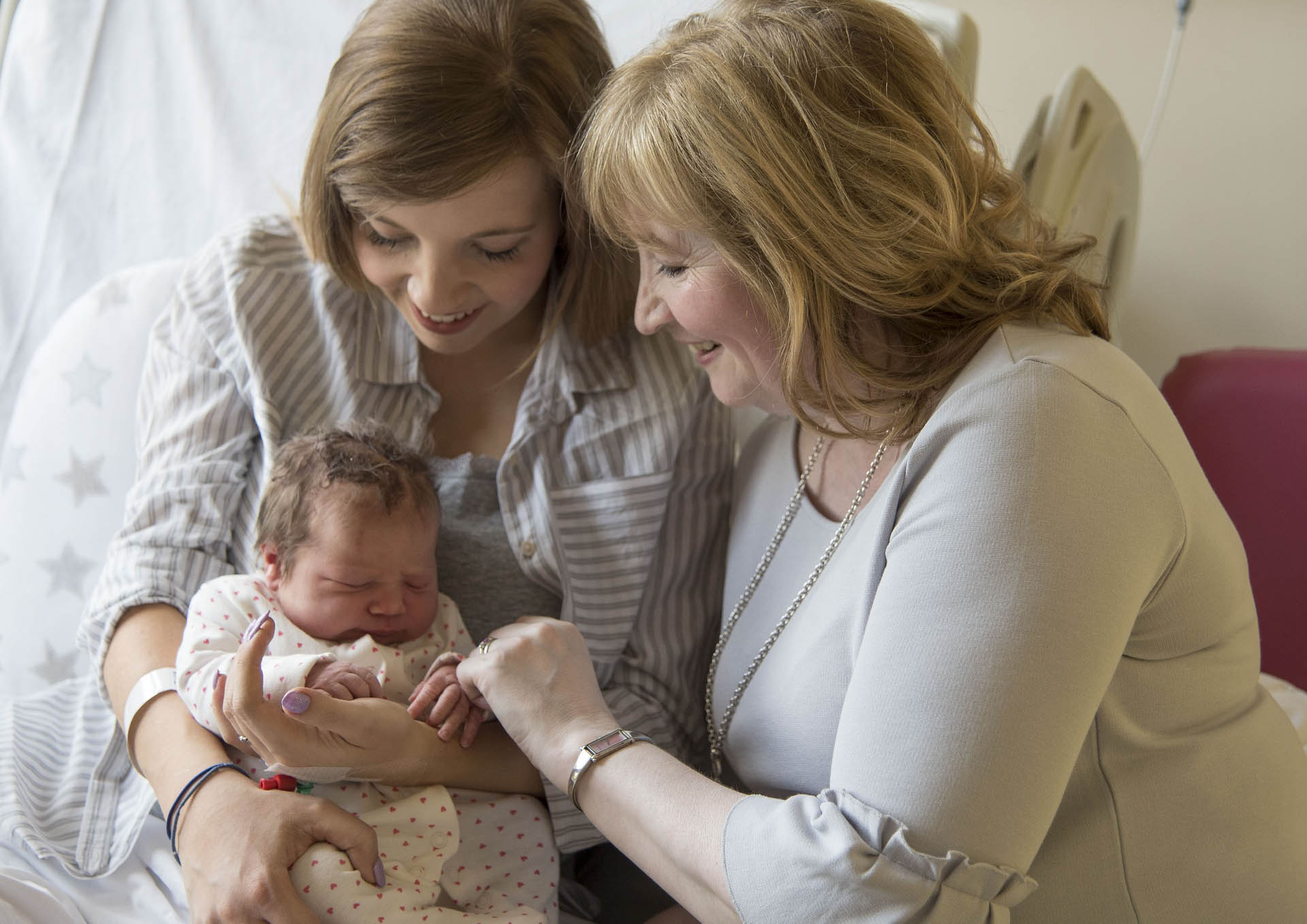 Mother and grandmother smiling while holding newborn baby