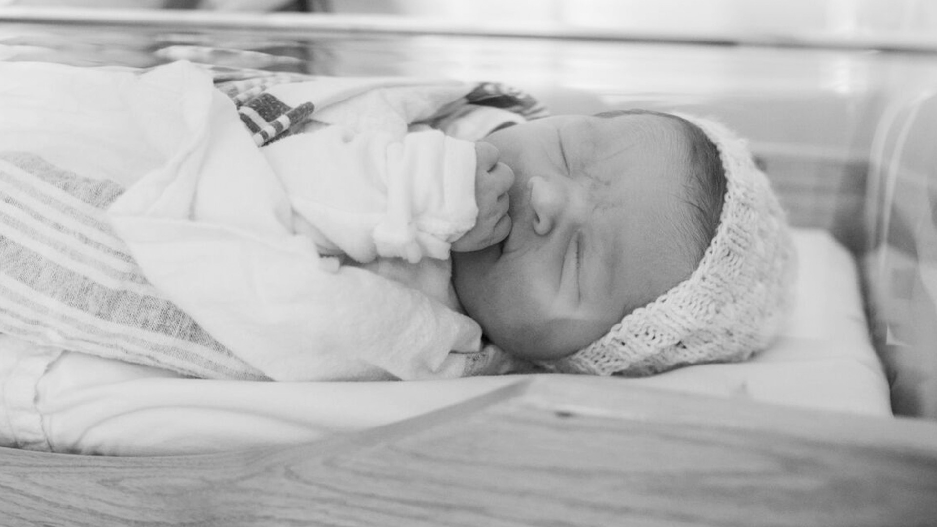 Sleeping newborn in hospital swaddle and bassinet